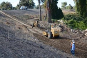 May contain: soil, slope, bulldozer, machine, gravel, and road