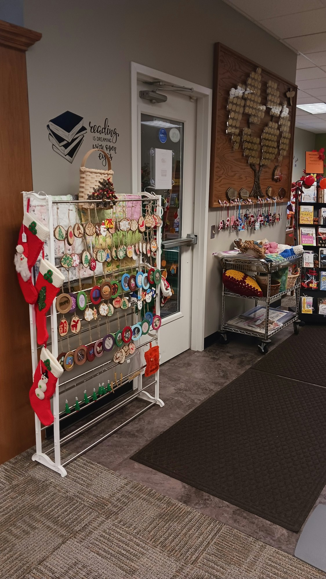 A market stall with various handmade items, including jewelry and Christmas decorations, displayed on shelves and hanging racks.