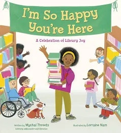 The image is the cover of a children's book titled "I'm So Happy You're Here," celebrating the joy of libraries.