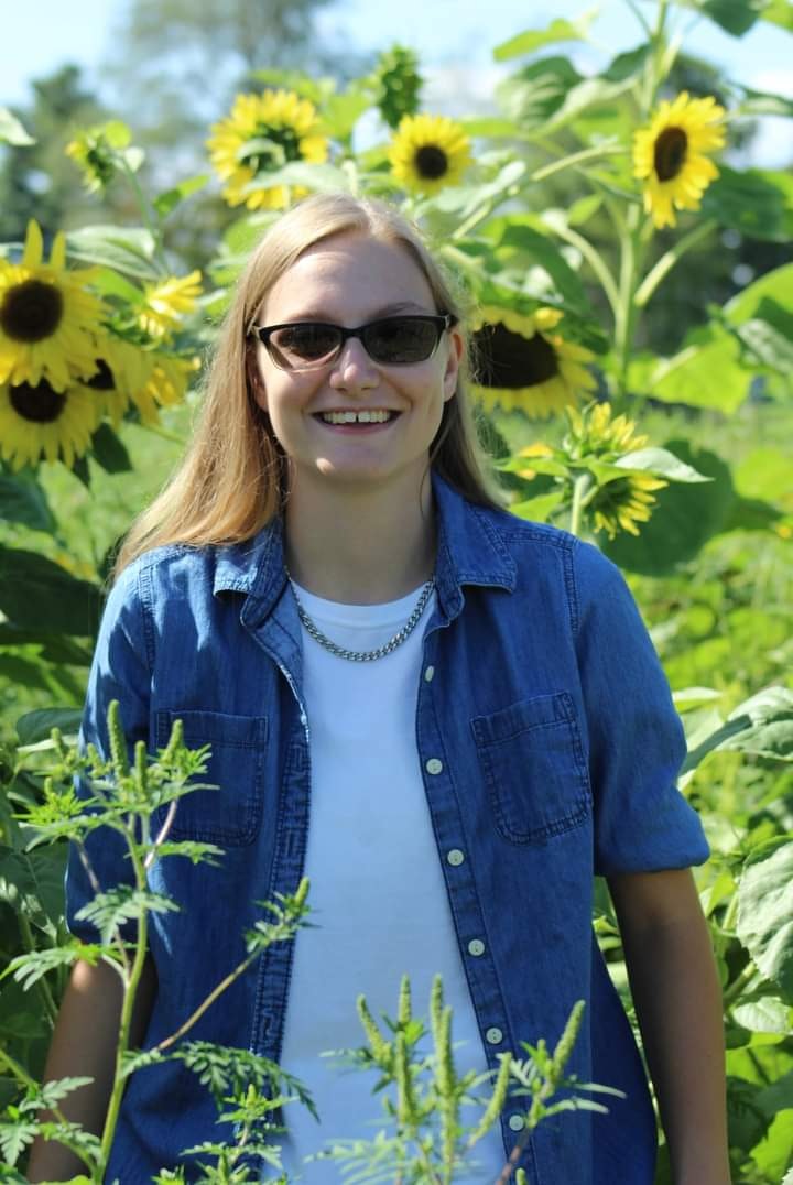 May contain: accessories, sunglasses, face, head, person, photography, portrait, herbal, herbs, plant, clothing, pants, flower, petal, sunflower, vegetation, jeans, jewelry, necklace, daisy, happy, smile, and coat