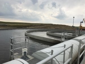 A water treatment plant with round sedimentation tanks under a cloudy sky.