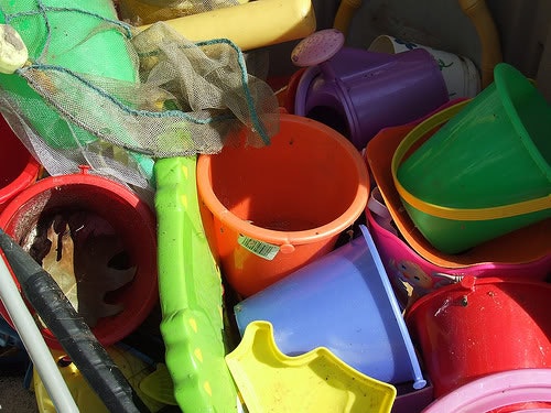 A pile of colorful plastic beach toys, including buckets, shovels, and a net.