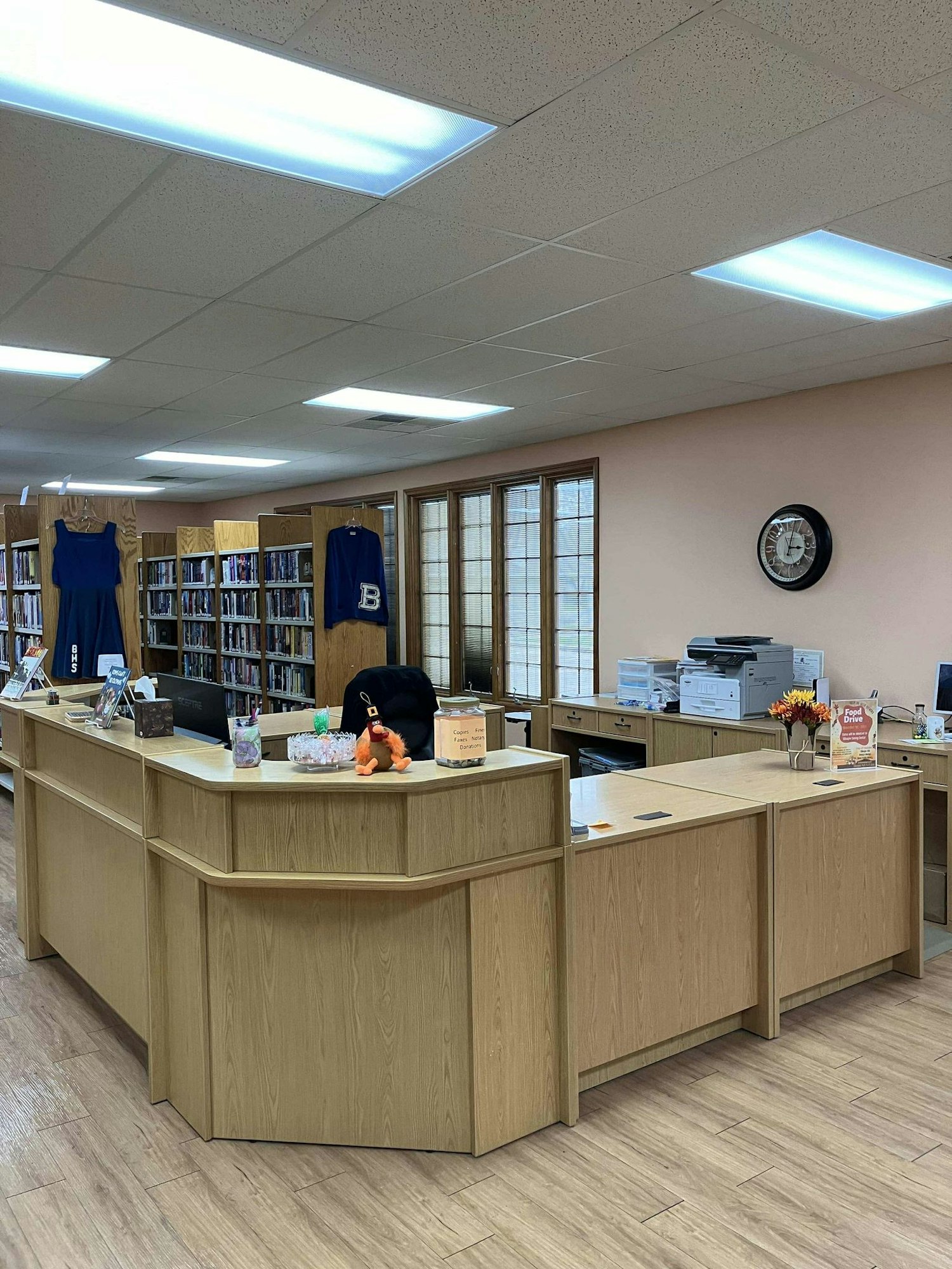 A library reception with bookshelves, a clock, jerseys, and decorative items.