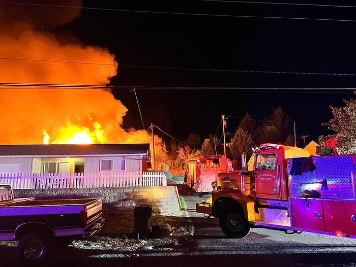 A house fire at night with firefighters and fire trucks on site.