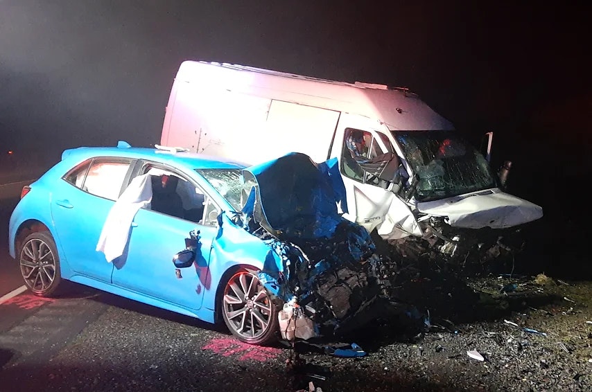 A car and a van with severe front-end damage from a collision, at night.