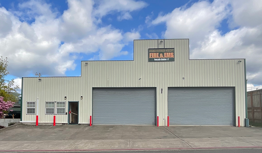 A fire station building with two large garage doors and a clear sky.