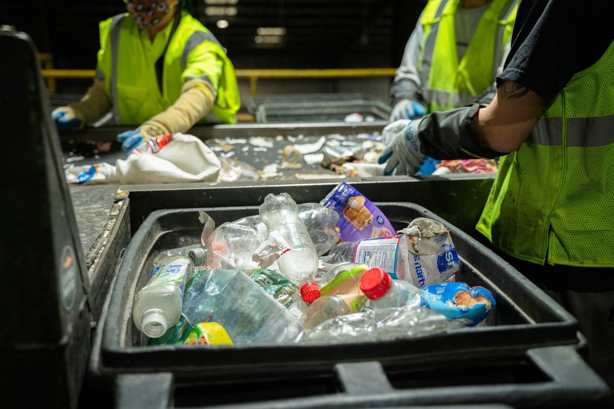Workers in green vests sorting plastics at the recycling facility