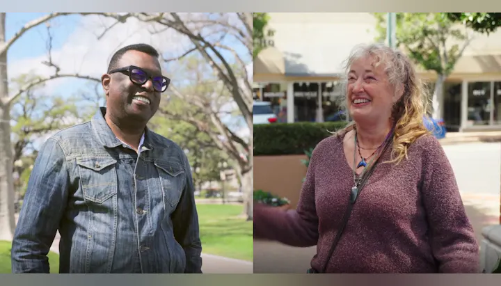 Two people outdoors, smiling and chatting on a sunny day.