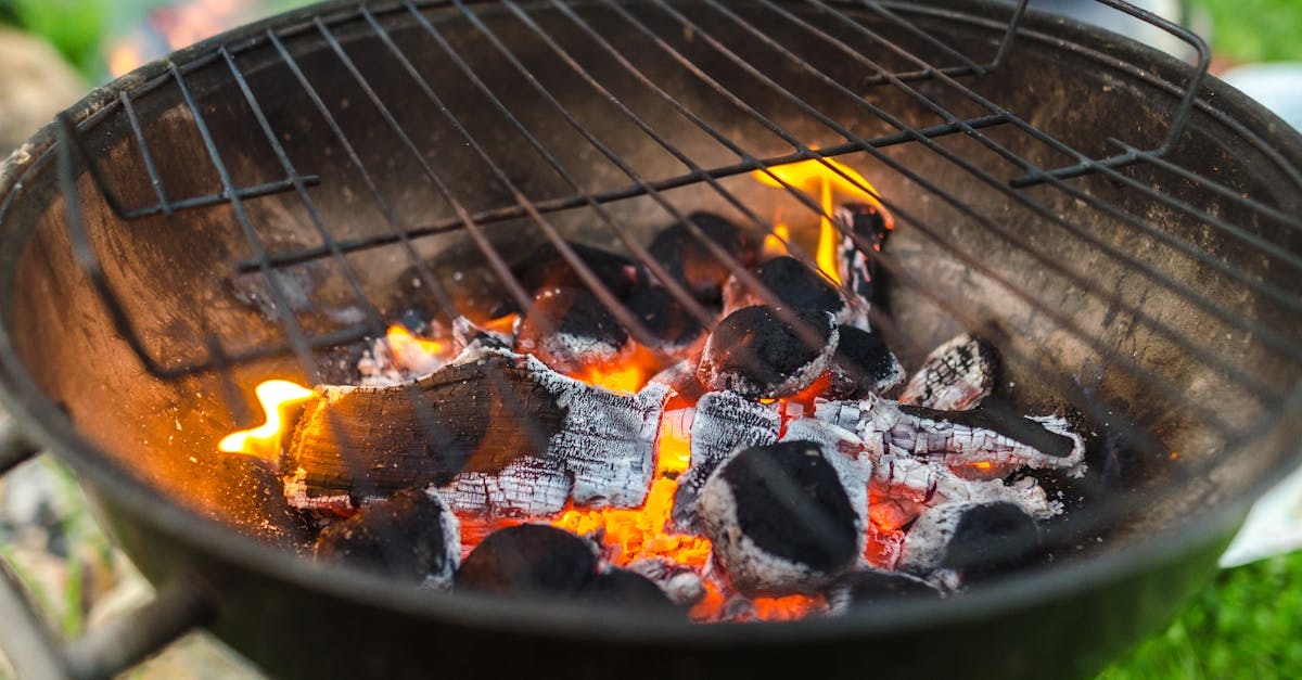 A charcoal grill with glowing coals and some flame, ready for barbecuing.