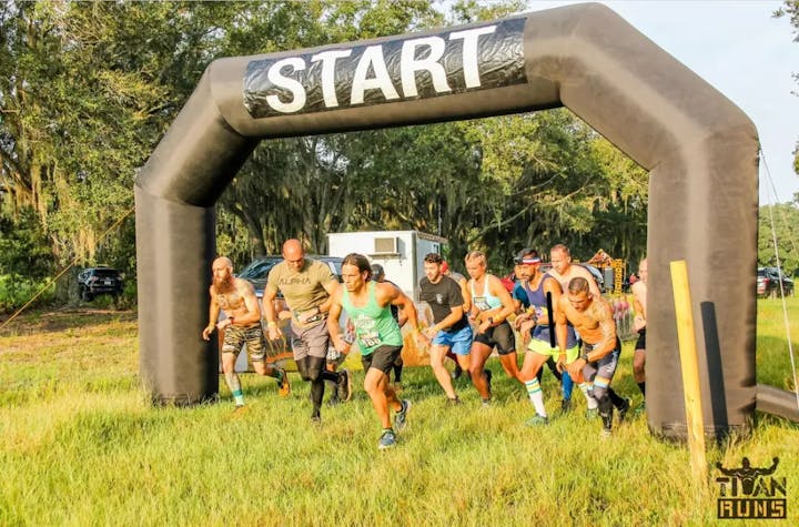 Runners starting a race under a "START" archway outdoors.