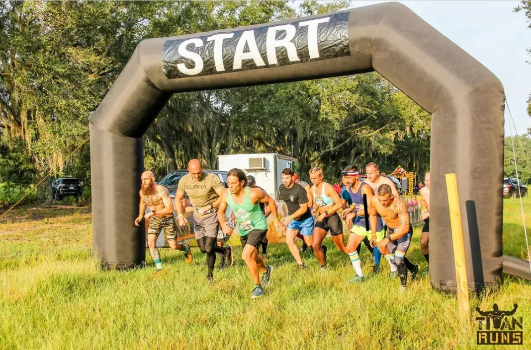 Runners starting a race under a "START" archway outdoors.