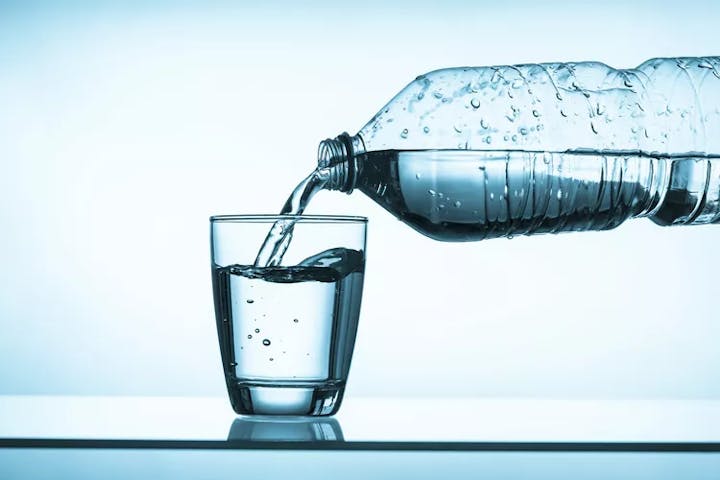 Water pouring from a plastic bottle into a glass.