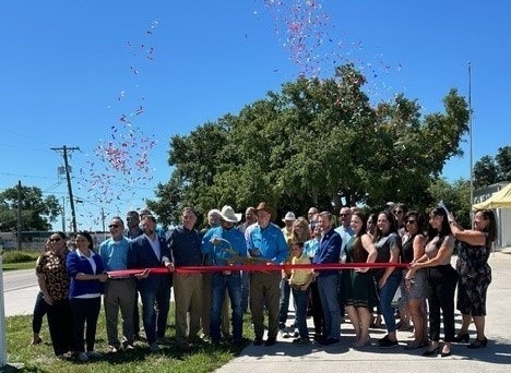 A group of people gathered for a ribbon-cutting ceremony, celebrating an event with confetti in the air.