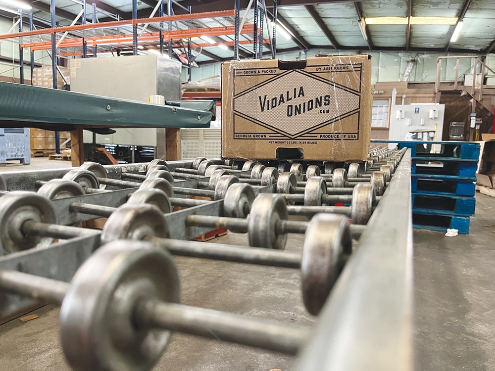 A box of Vidalia onions on a conveyor belt in a distribution facility.