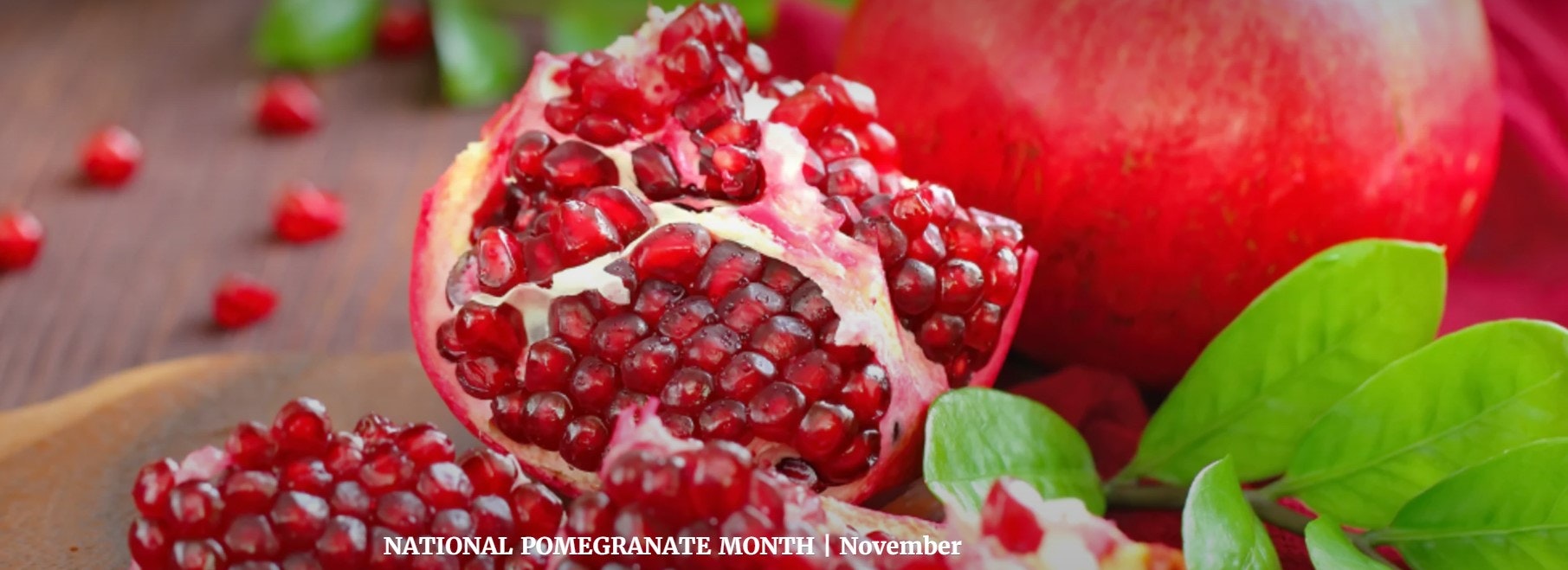 Pomegranate with seeds exposed, leaves, text: "NATIONAL POMEGRANATE MONTH | November".