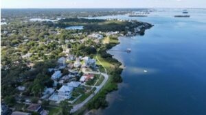 Aerial view of a coastal neighborhood with houses, roads, and a large body of water.
