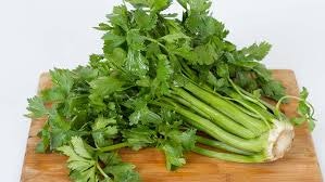 A bunch of fresh celery on a wooden cutting board.