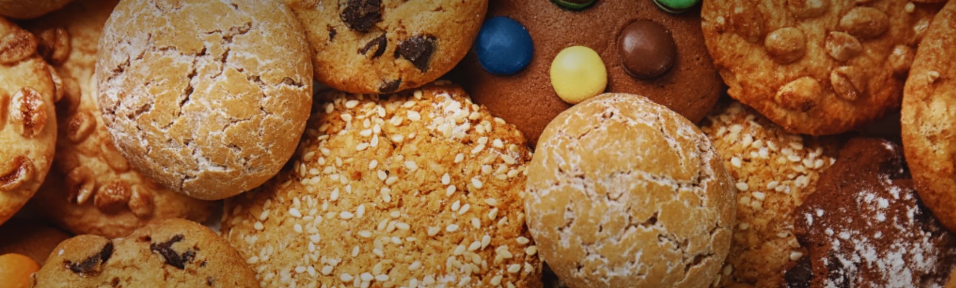 A variety of cookies with different toppings like chocolate chips, nuts, and candies.