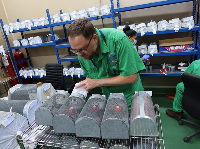 Alex Arp shown inspecting live specimens of screwworm flies in a screwworm lab with staff members at a facility in Panama.