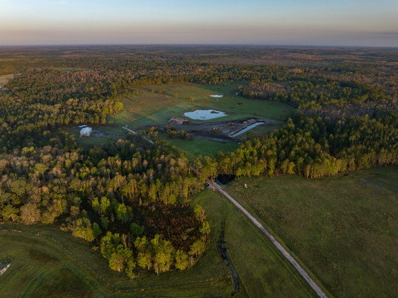 Aerial view of a rural landscape with fields, trees, a road, and small water bodies.
