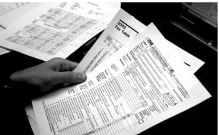 A person holding tax forms and documents.