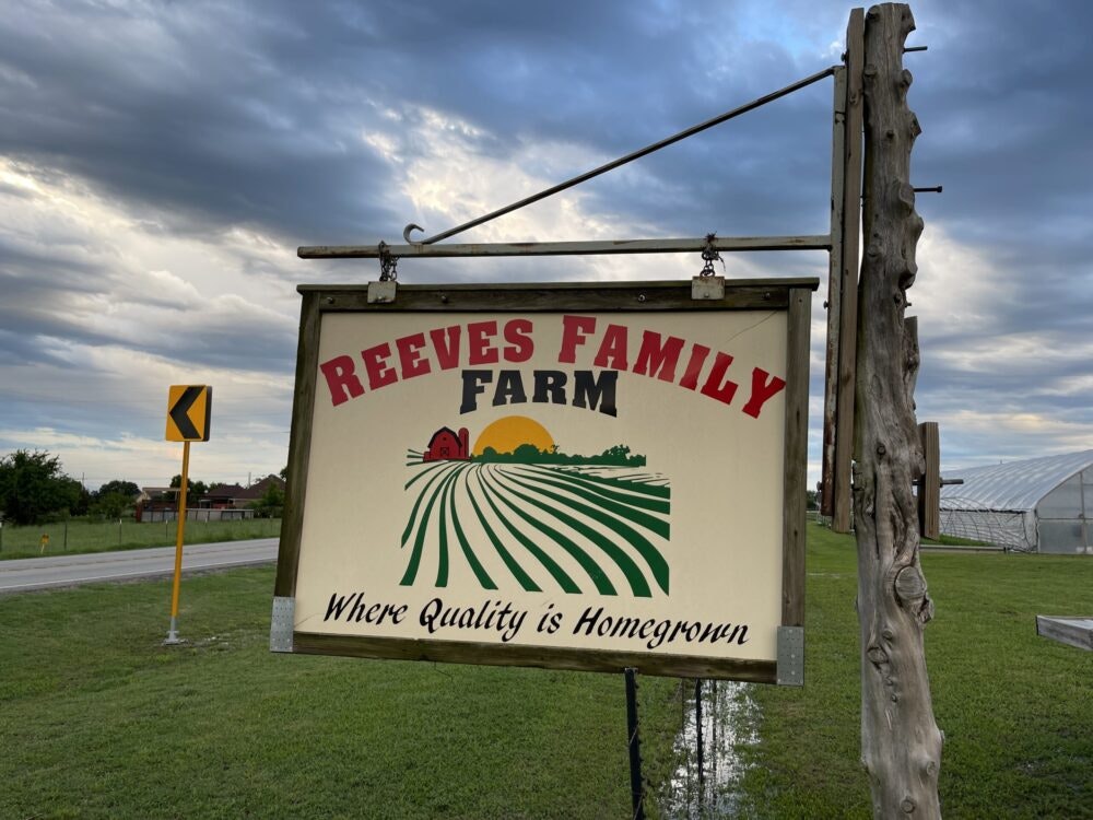 Sign for "Reeves Family Farm" with slogan "Where Quality is Homegrown" in a rural setting.