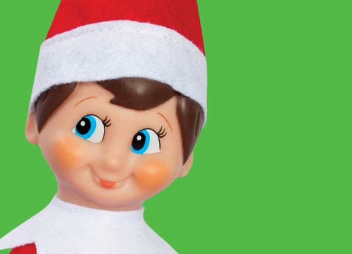 An elf doll with a red Santa hat and rosy cheeks against a green background