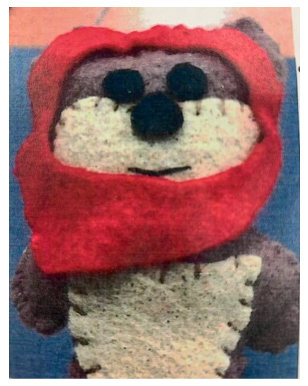A stuffed toy resembling an animal with a red hood and beige body.