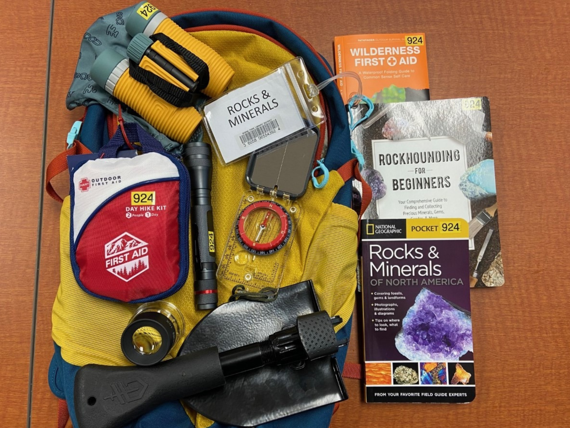 Backpack, binoculars, flashlight, first aid kit, compass, shovel, field guides, and a book on rockhounding and minerals.
