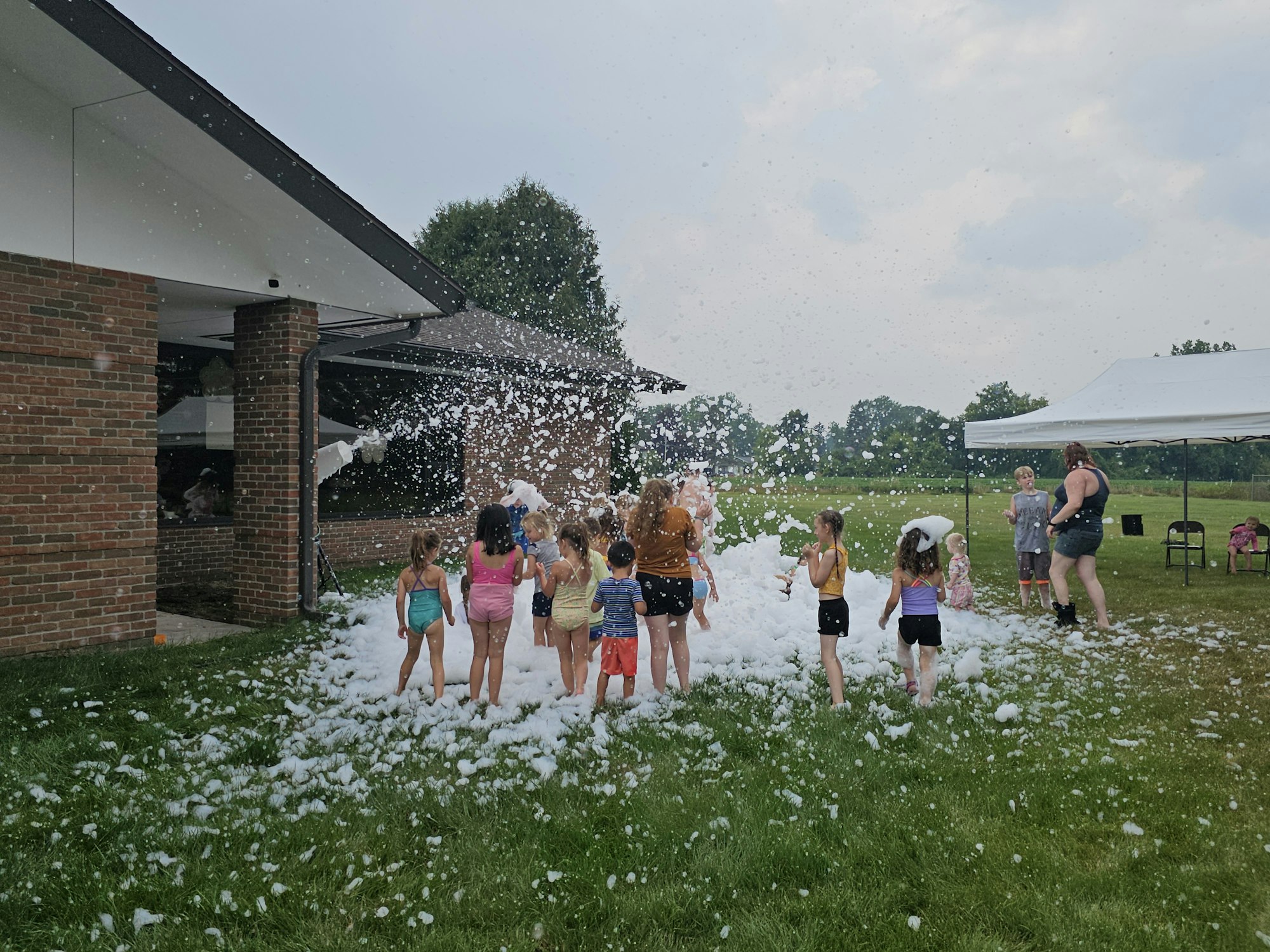 Children playing with foam outdoors near a building.