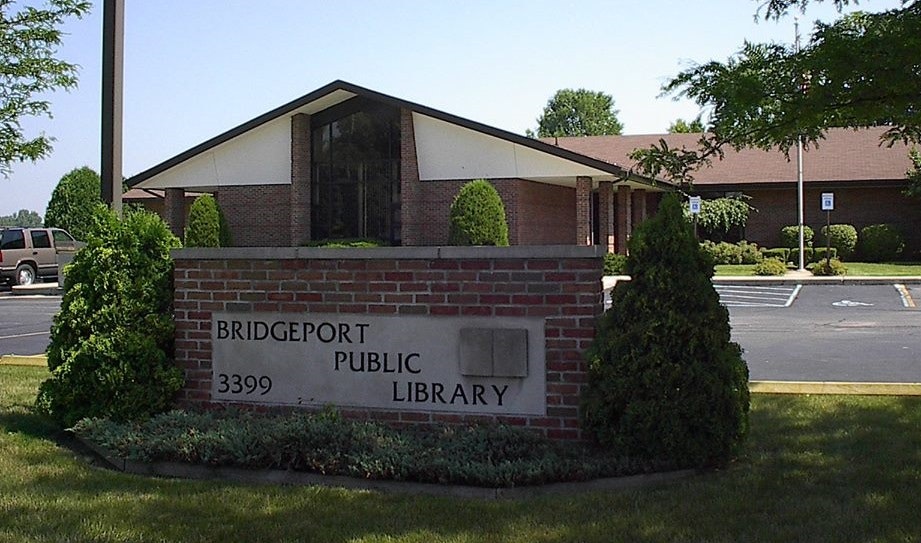 Bridgeport Public Library with parking lot and trees in the background.
