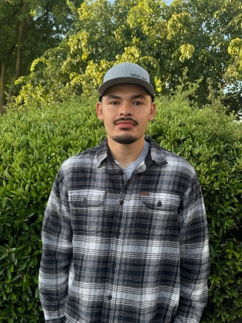 May contain: face, head, person, photography, portrait, baseball cap, cap, clothing, hat, plant, vegetation, shirt, green, adult, male, man, tree, and standing