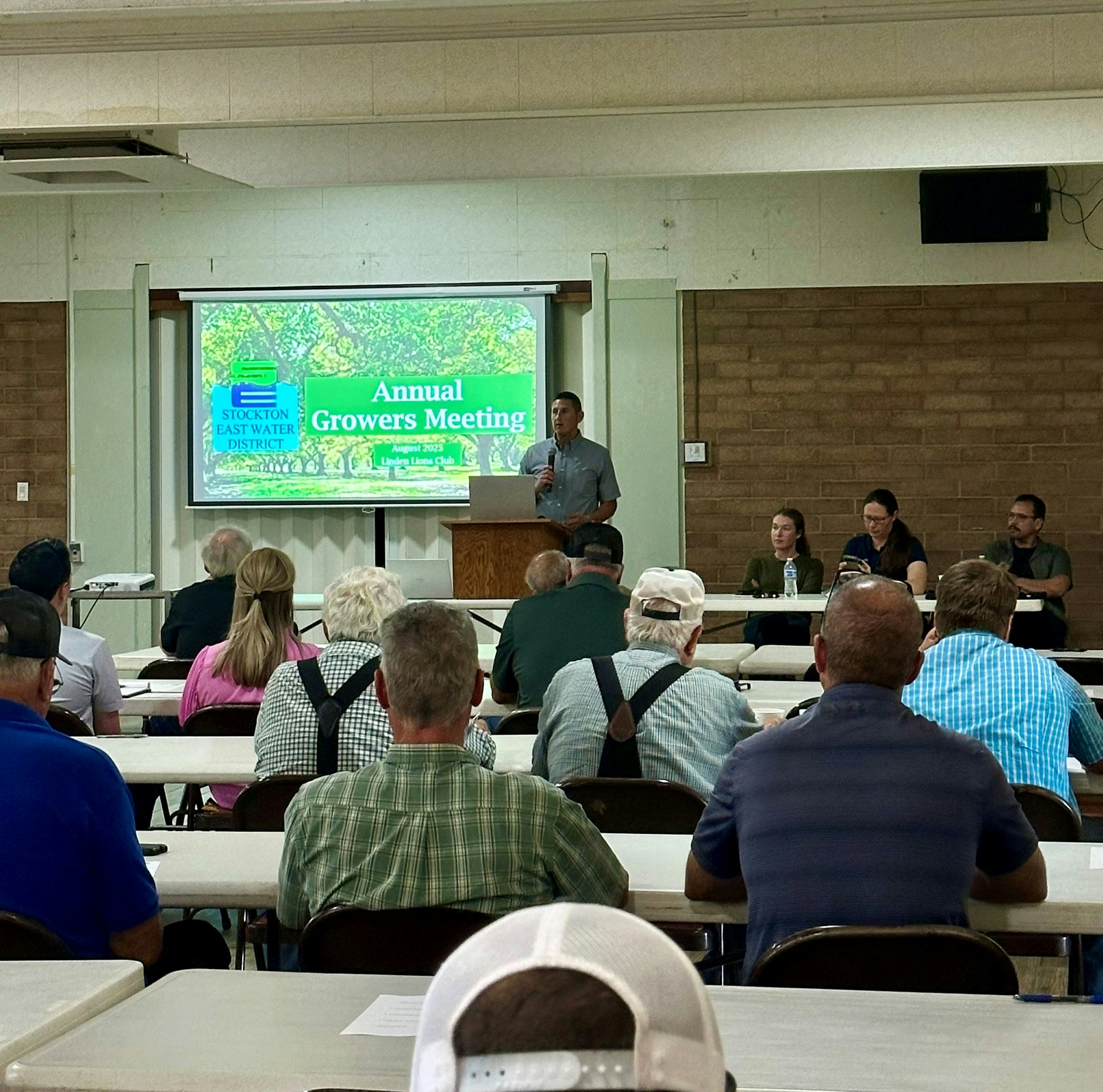 A speaker presents at the "Annual Growers Meeting" with attendees seated at tables, and a panel of speakers is at the front.