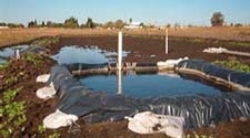 A small-scale wastewater treatment system with ponds and pipes, probably for agriculture, set in a rural area.