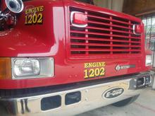 A red fire truck labeled "ENGINE 1202" viewed up-close.