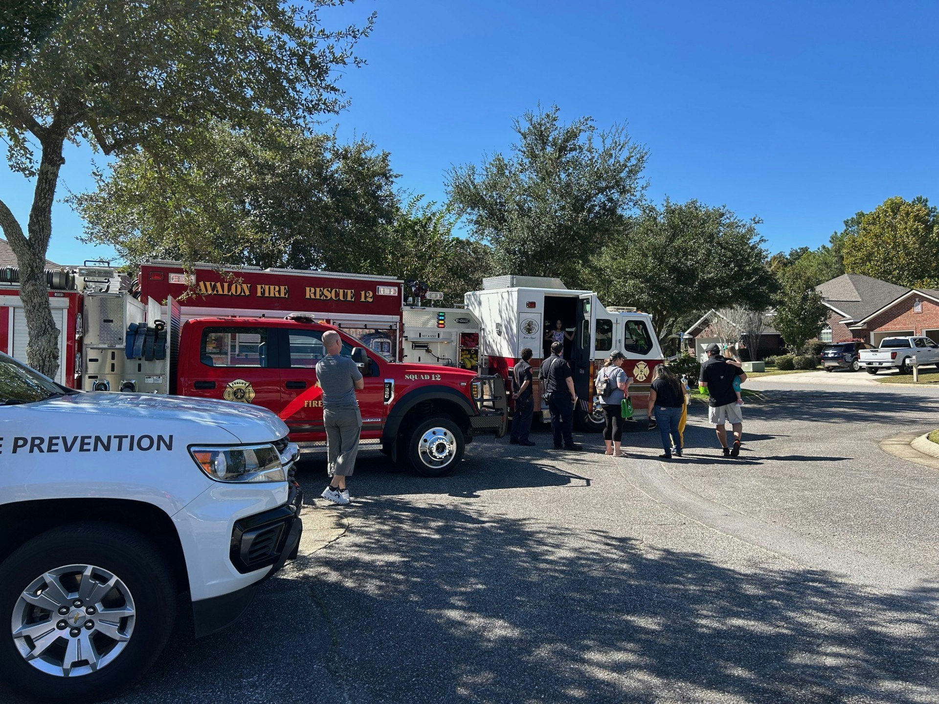 Fire trucks and a fire prevention vehicle parked on a street, with people gathered around.