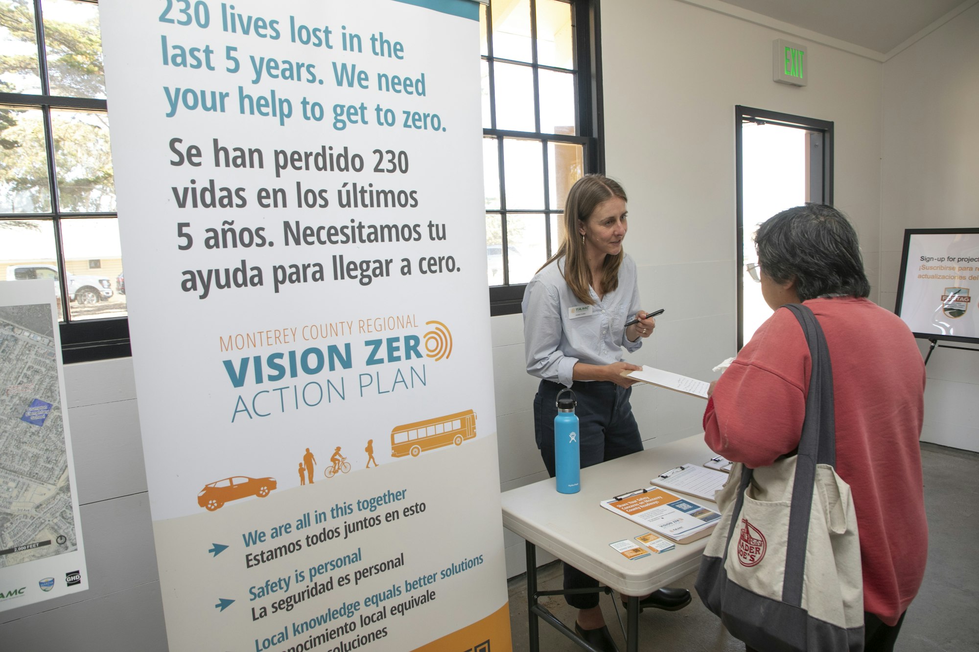 Two people at a booth for Monterey County's Vision Zero Action Plan, aiming to reduce traffic fatalities.