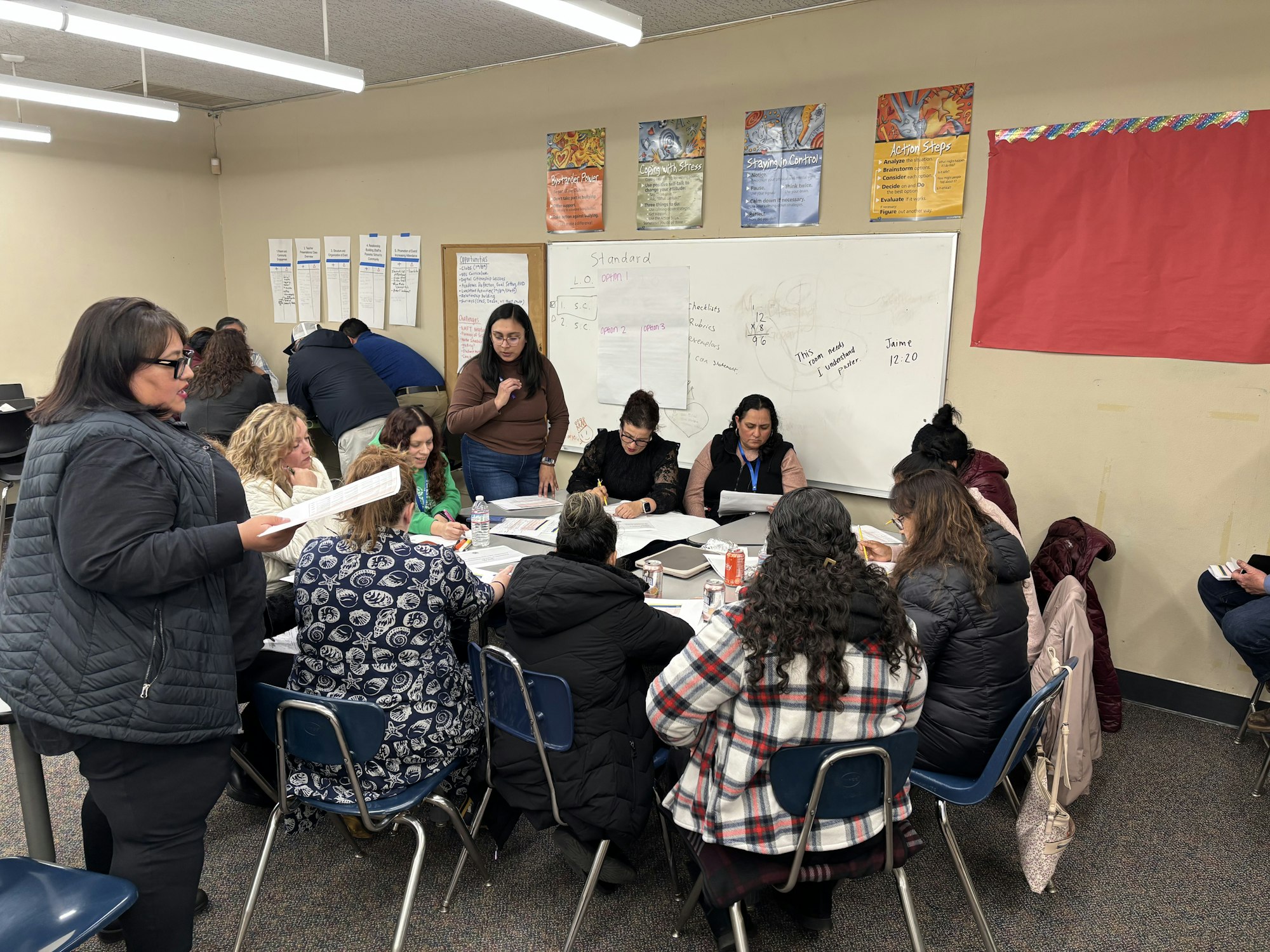 A group of people is engaged in a collaborative meeting or workshop, discussing materials and taking notes.