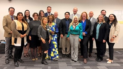 A group of diverse individuals posing for a photo in a professional setting, likely during an event or meeting.