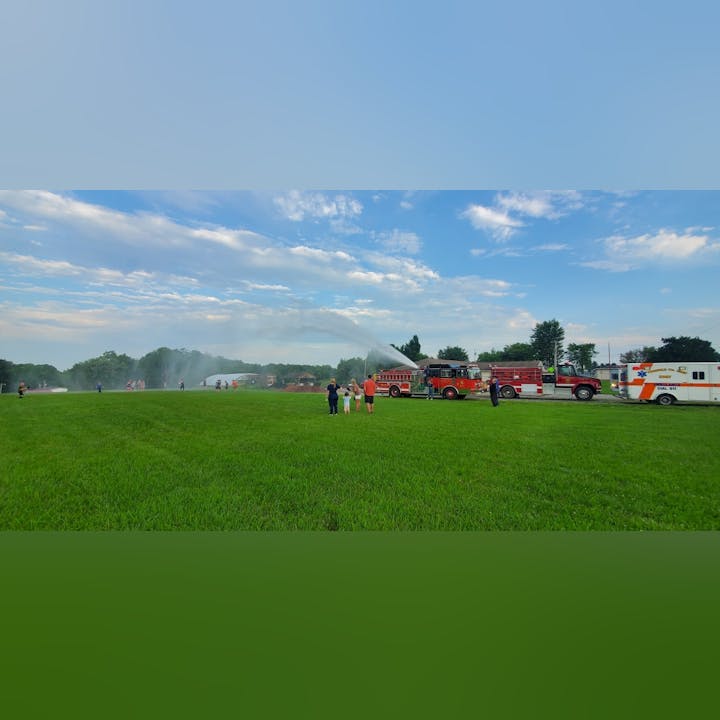 Photo of a green grassy area and emergency response vehicles