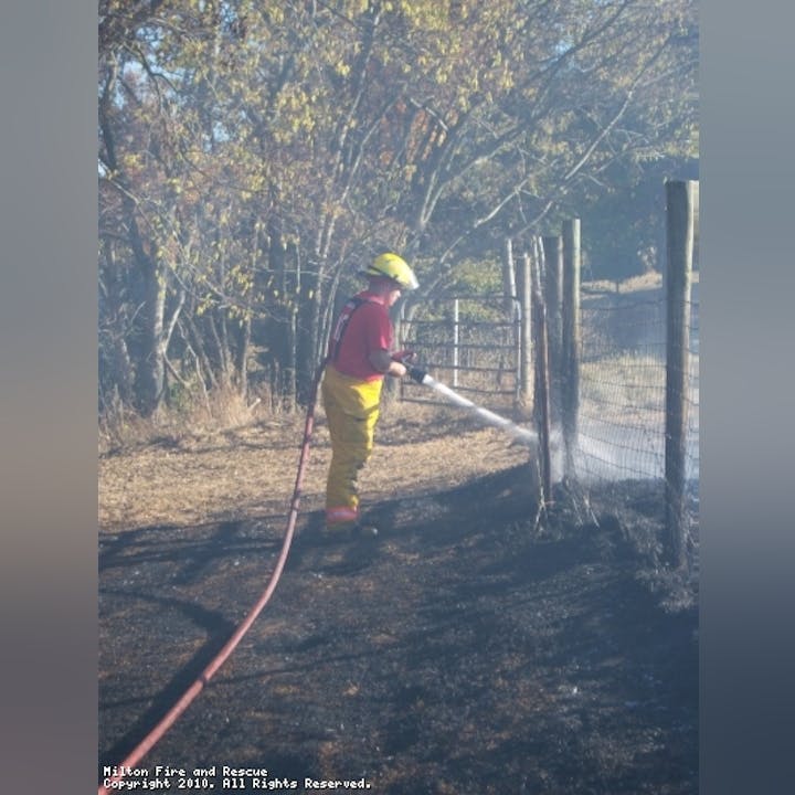 Photo of someone putting out a field fire