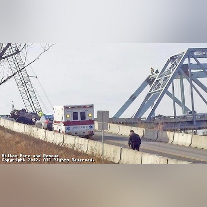 Photo of an over turned vehicle on a bridge on ramp