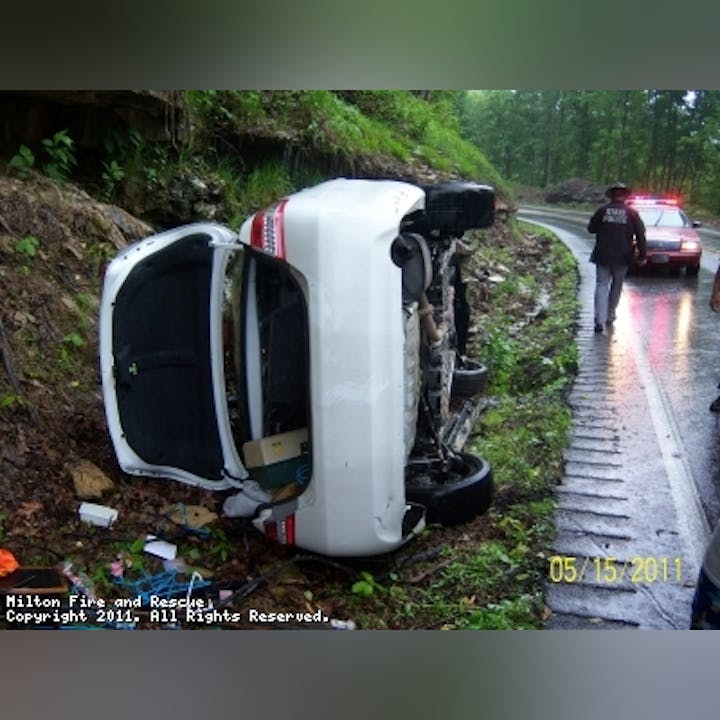 Photo of a white car turned up on it's side