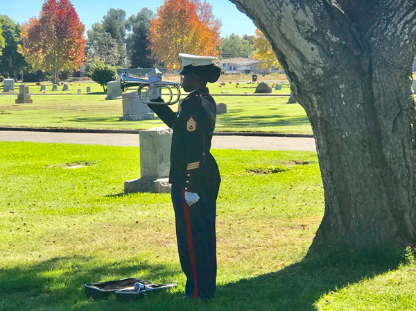 Photo of a military person in a cemetery playing an instrument
