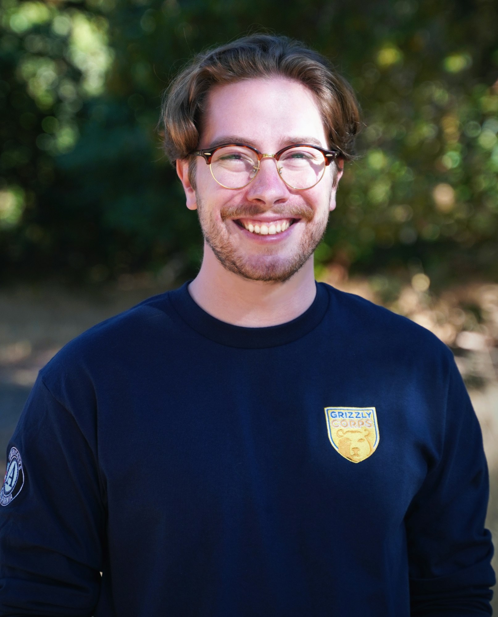 May contain: clothing, t-shirt, face, head, person, photography, portrait, long sleeve, sleeve, happy, smile, accessories, glasses, adult, male, man, and beard