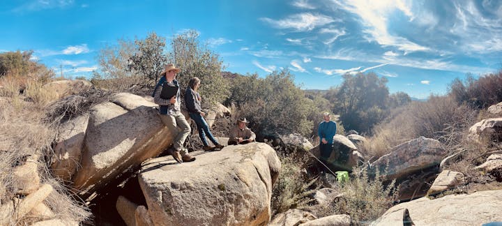 May contain: rock, nature, outdoors, wilderness, adventure, hiking, leisure activities, person, clothing, footwear, shoe, hat, plant, vegetation, photography, scenery, bag, and glove