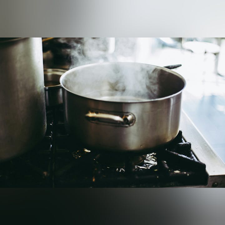 A pot on a stove with steam rising, indicating boiling water.