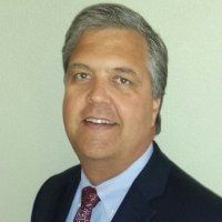 A smiling man with gray hair, wearing a suit and tie.