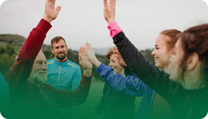 Group of people outdoors, smiling and giving high fives.