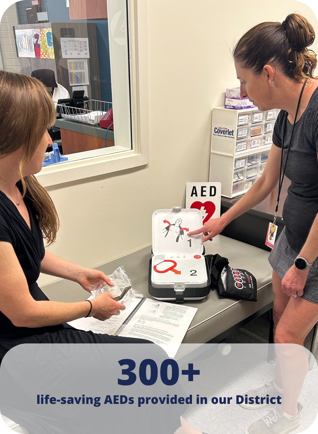 Two people with an AED device; text says "300+ life-saving AEDs provided in our District."